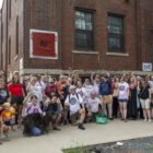People pose outside a brick building with raised fists.
