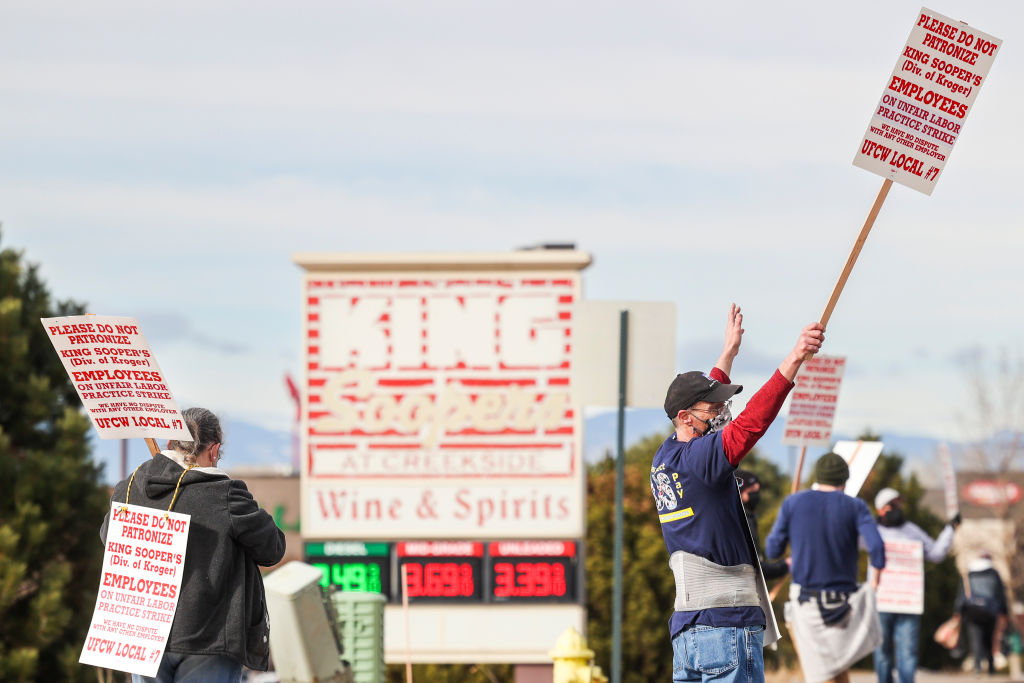 A man holds a sign saying “Please do not patronize King Sooper’s employees, on unfair labor practice strike, UFCW Local #7”.