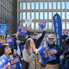 People protest with signs saying “We all deserve better!” and “AFGE.”.