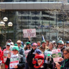 Public sector workers represented by AFSCME rally for May Day wearing green and holding up signs.